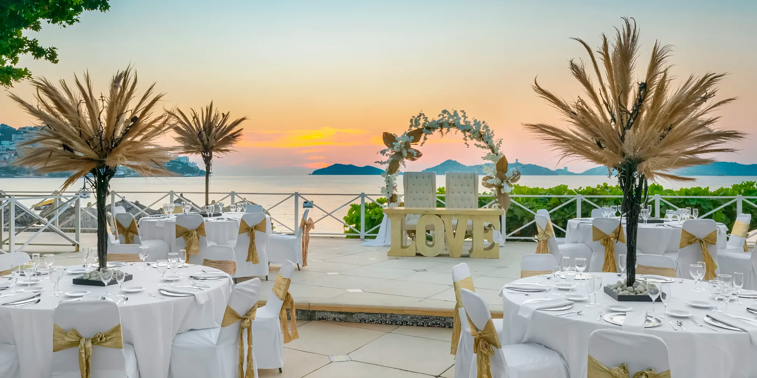 Sunset wedding setup at Dreams Acapulco Resort: beautifully decorated tables and a "LOVE" sign by the sea for your perfect destination wedding.