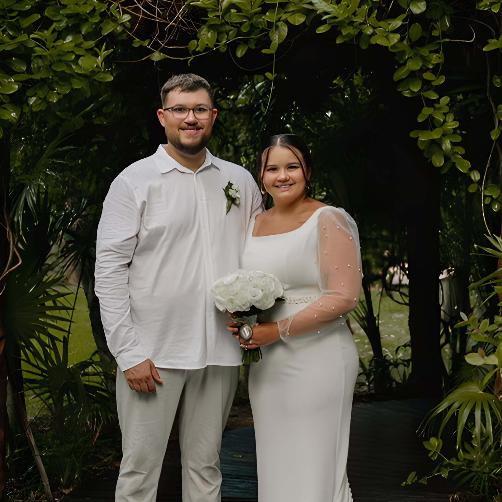 Lauren and Julian's Wedding at Sandos Playacar posed for a photo in a garden.
