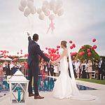 A bride and groom holding balloons in front of a pool for their Miami wedding.