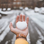 A person holding a snowball in their hand, perfect for winter proposal ideas.