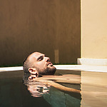 A man is lounging in a pool at a spa resort.