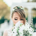 A beautiful bride with a half-up wedding hairstyle holding a bouquet of flowers.
