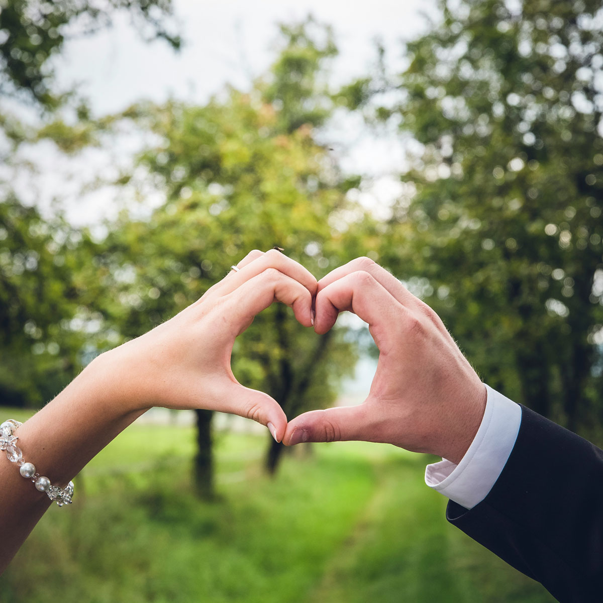 A bride and groom celebrating their 2 year anniversary by making a heart shape with their hands.