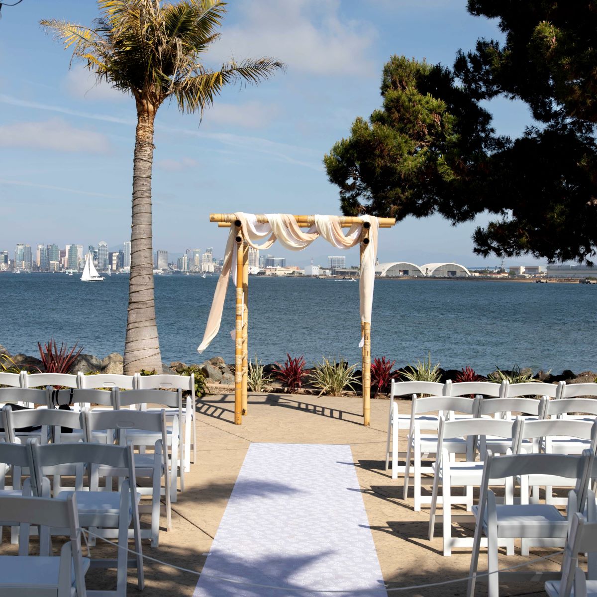 A wedding industry setup with white chairs and a view of the ocean.