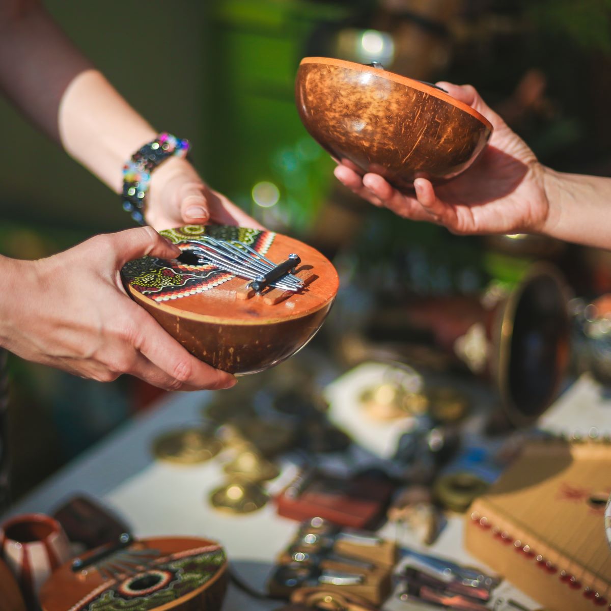 Two people are holding wooden bowls crafted by local artists on a table.