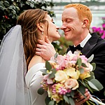 A bride and groom hugging in a greenhouse for their wedding poses.