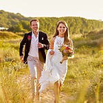 A bride and groom running through the sand on a beach during their stress-free wedding.