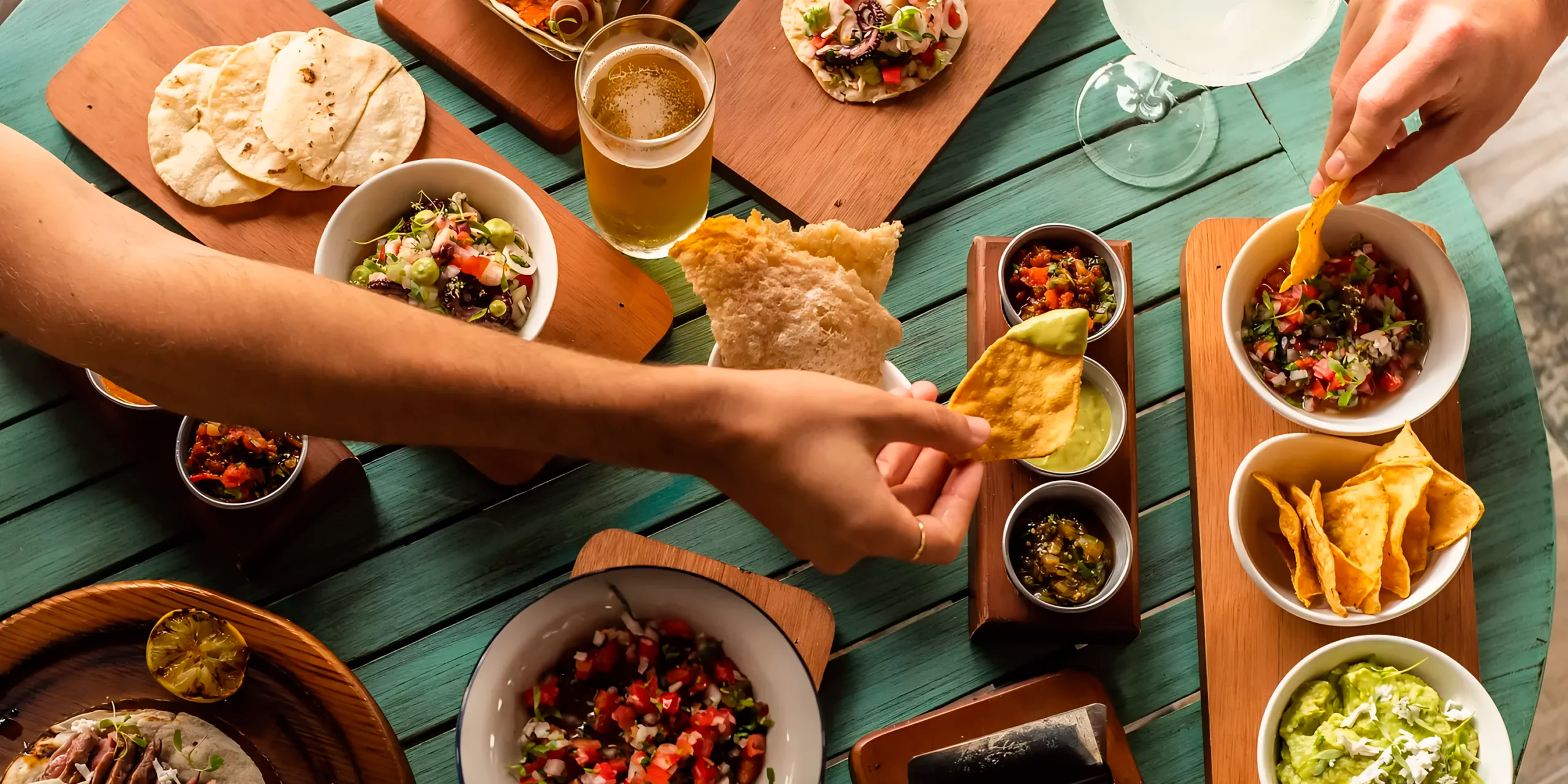 Hands eagerly reach for chips and salsa at Margaritaville Island Reserve Riviera Maya, setting the festive tone for a memorable destination wedding celebration.