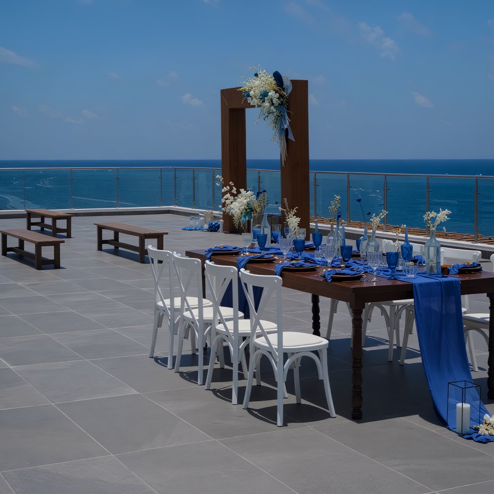 An elegant outdoor wedding dining setup with blue accents, beautifully overlooking the ocean.