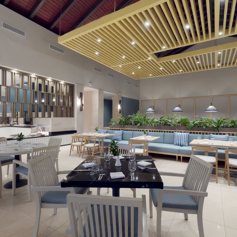 A contemporary restaurant interior featuring wooden accents, with tables and chairs neatly arranged, perfect for hosting a destination wedding.
