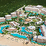 Aerial view of Secrets Playa Blanca Costa Mujeres, a luxurious beachfront resort with multiple swimming pools and lush green surroundings.