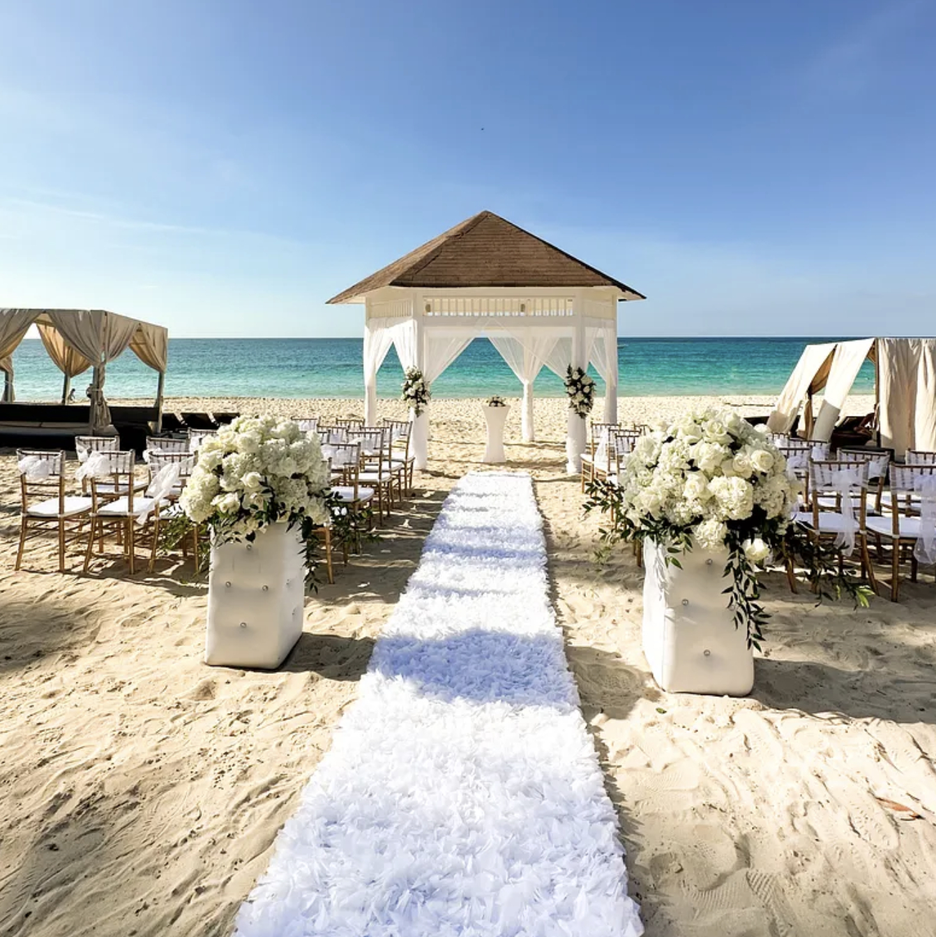 A beach wedding ceremony set up on the sand.