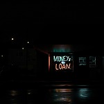 A neon sign that says money and loan at night.