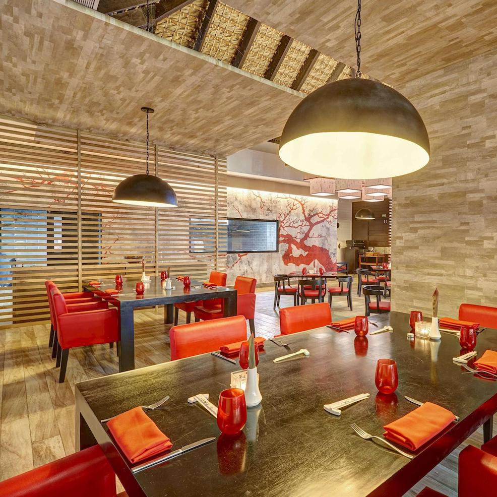 A restaurant with red chairs and a wooden ceiling.
