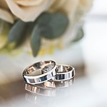 Two wedding rings on a glass surface.