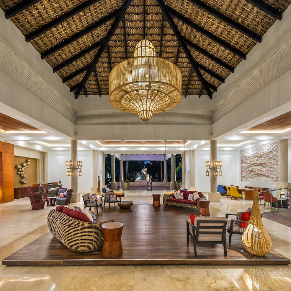 The lobby of a hotel with wooden furniture and a chandelier.