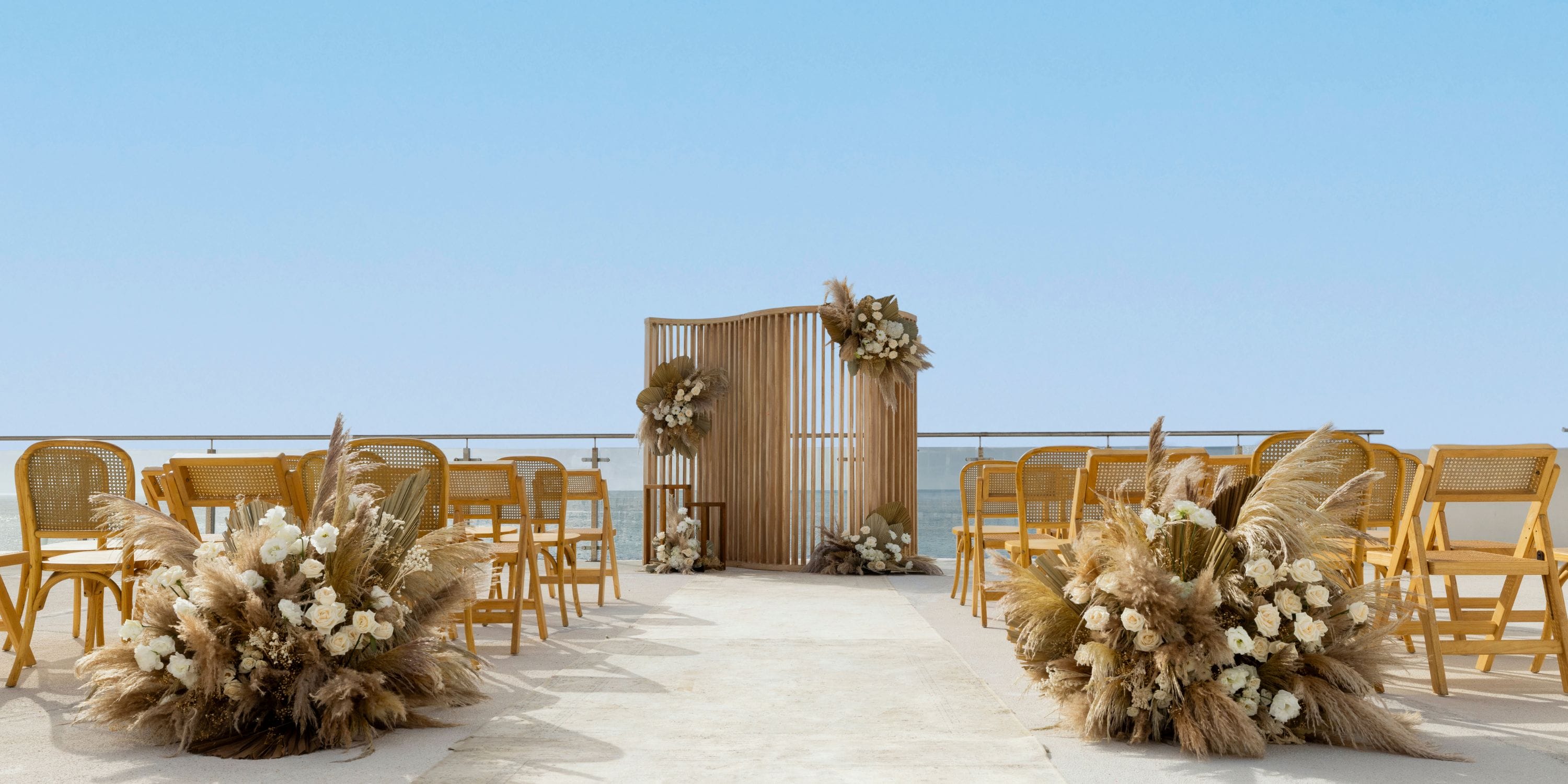 Destination wedding setup at AVA Resort Cancun featuring wooden chairs, floral accents, and a simple backdrop.