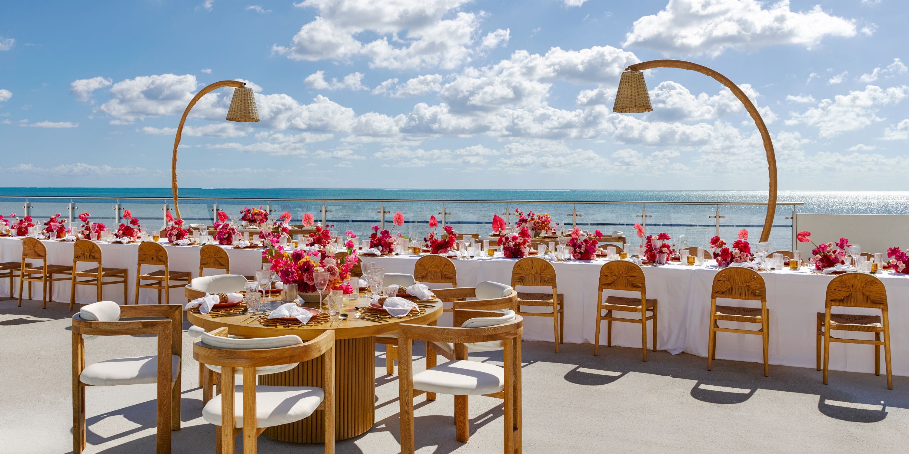 Two long tables with pink floral centerpieces set for a destination wedding at AVA Resort Cancun.