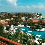 An aerial view of Secrets Playa Blanca reveals a dream destination wedding venue, featuring stunning pools, swaying palm trees, and lush greenery.