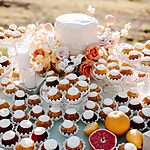 A festive table adorned with assorted cupcakes, citrus fruits, and colorful floral arrangements as wedding cake alternatives.