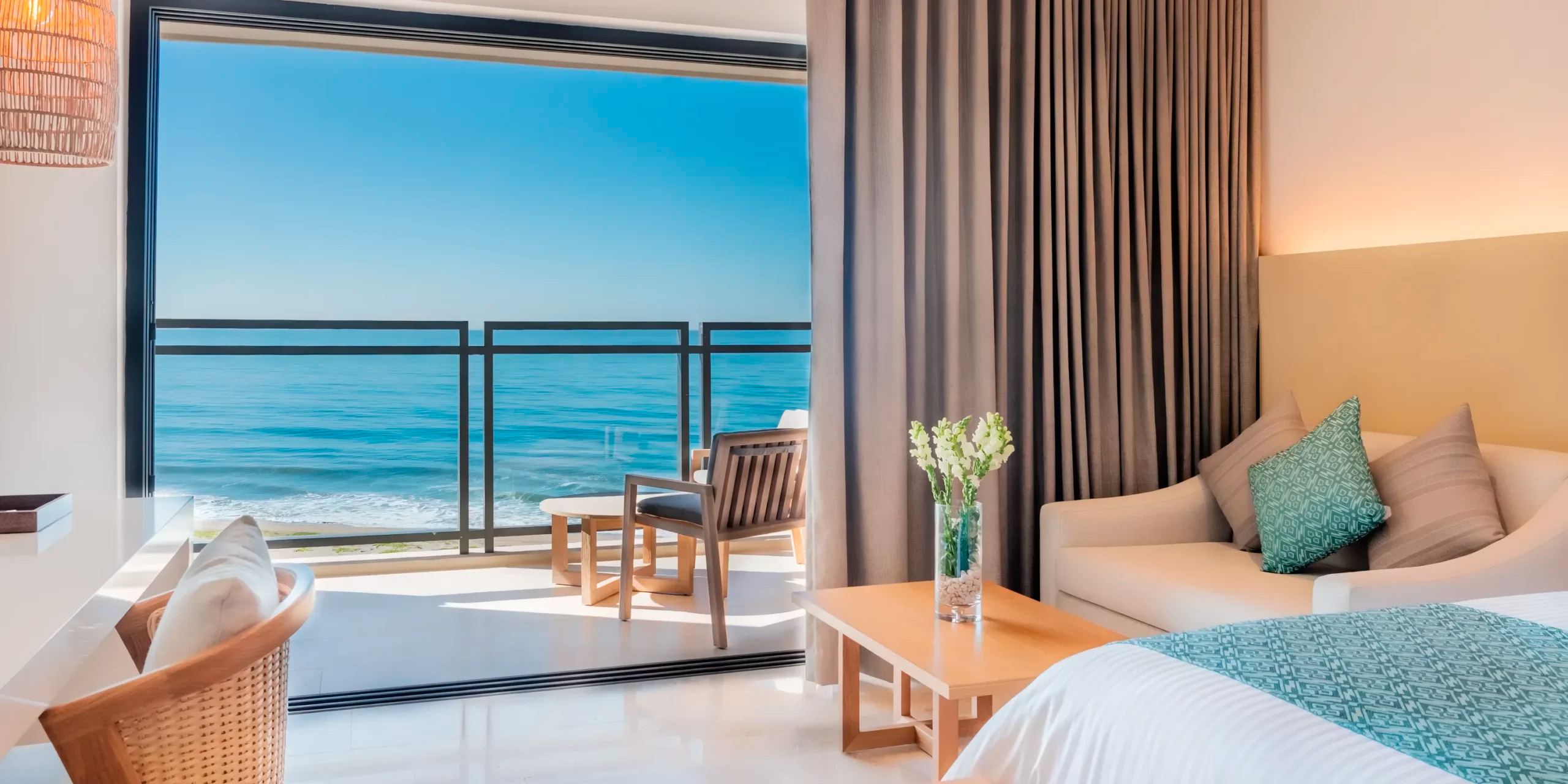 Dreams Estrella del Mar provides a perfect setting for a destination wedding, featuring ocean view rooms with balcony seating. The interior is elegantly designed with a beige sofa, wood table, and a comfortable teal bed, making it an ideal venue for your memorable celebration.