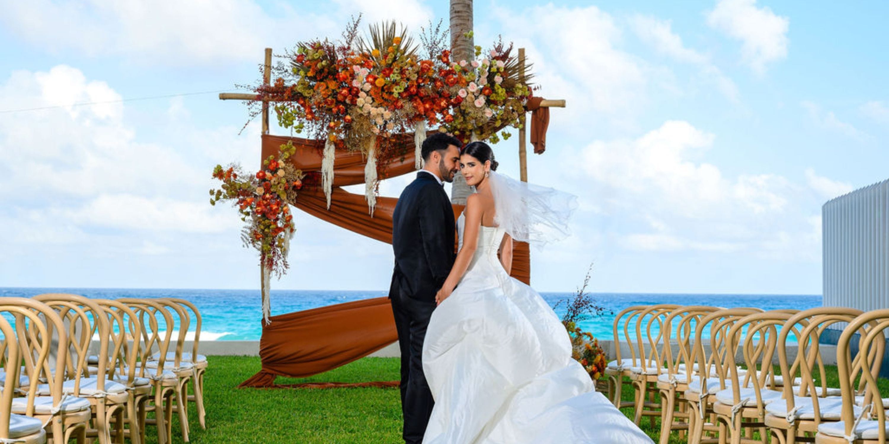 Bride and groom at a destination wedding altar by the ocean at Hilton Cancun Mar Caribe, chairs all around.