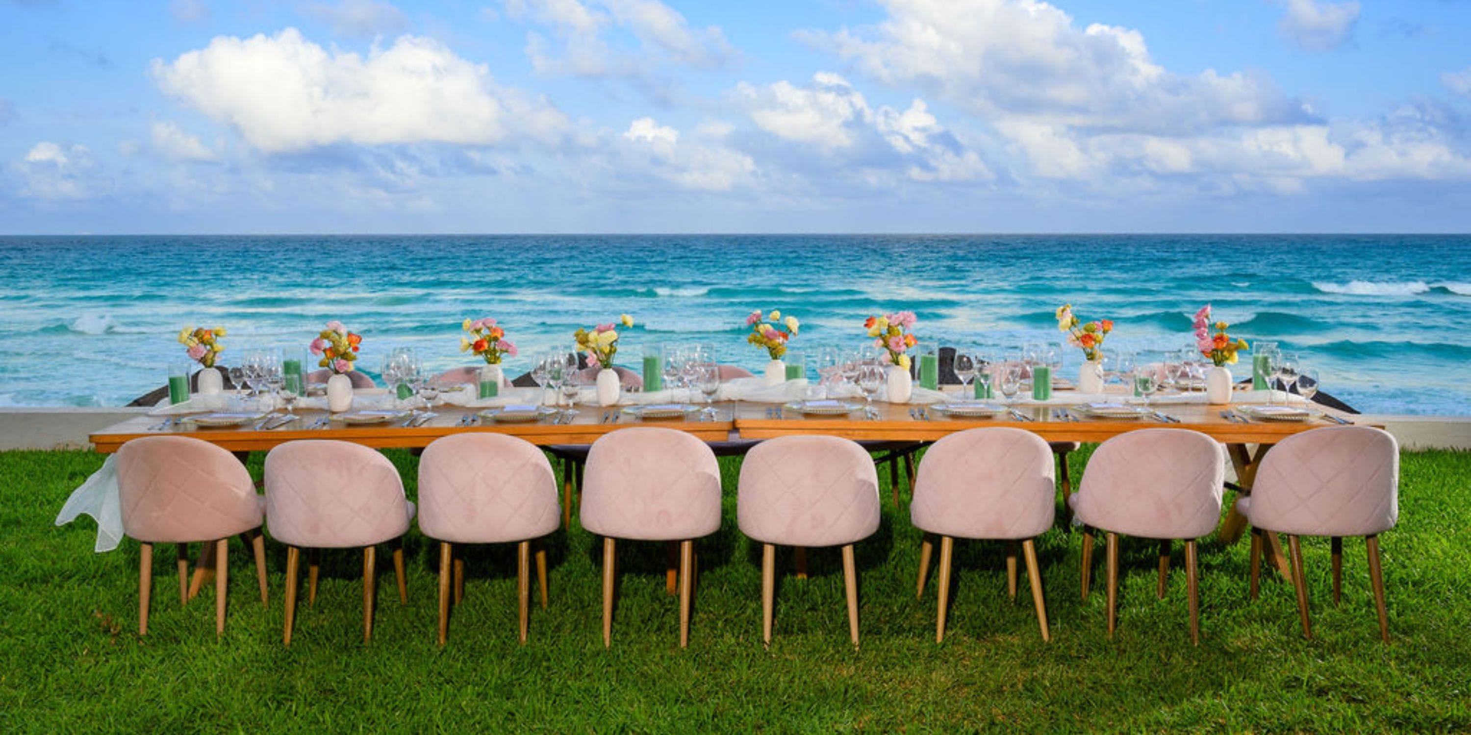 Hilton Cancun Mar Caribe showcases a long oceanfront dining table with pink chairs, perfect for a destination wedding.