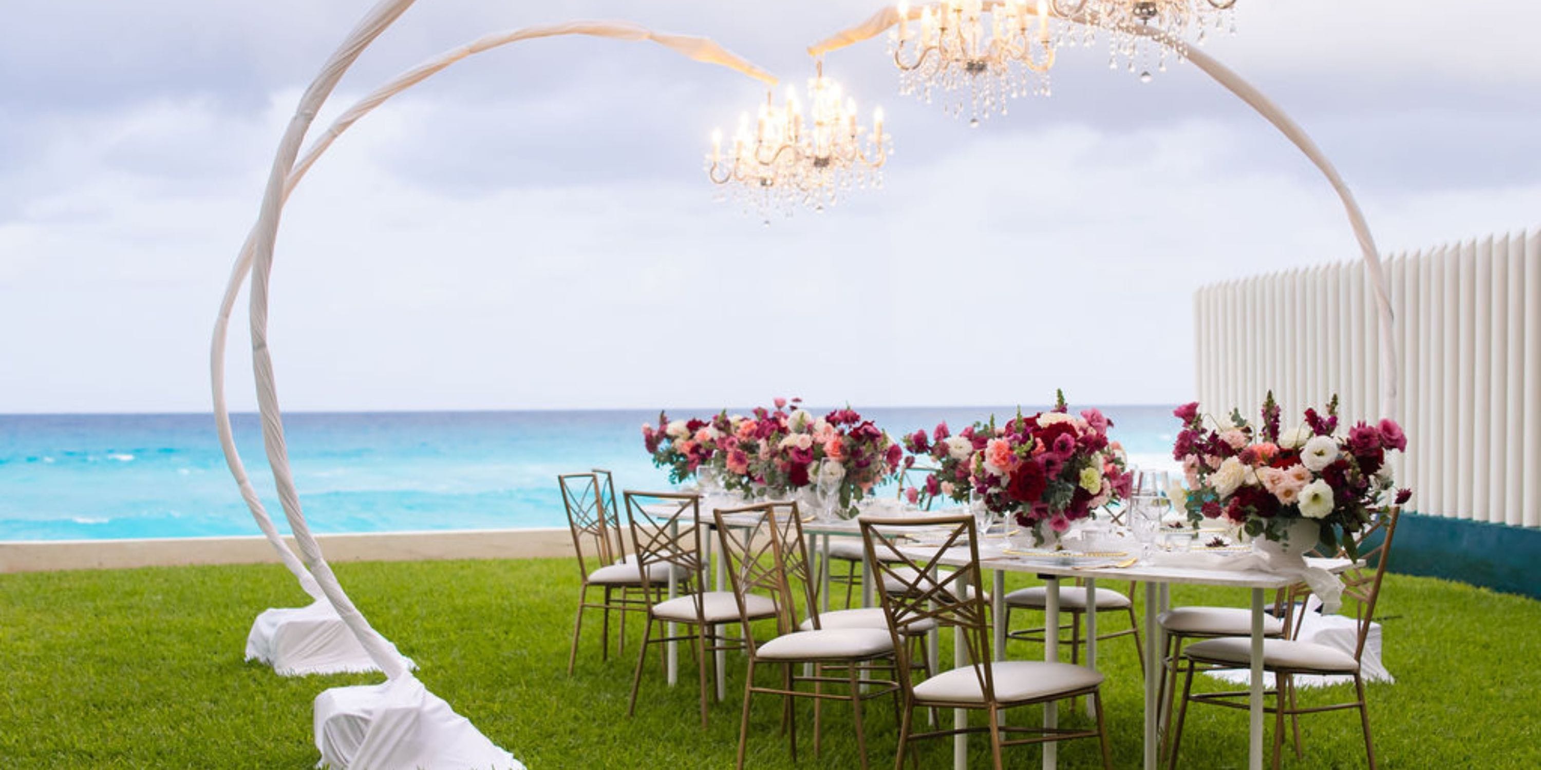 Hilton Cancun Mar Caribe: Elegant outdoor wedding table with florals, chandeliers, and ocean views.