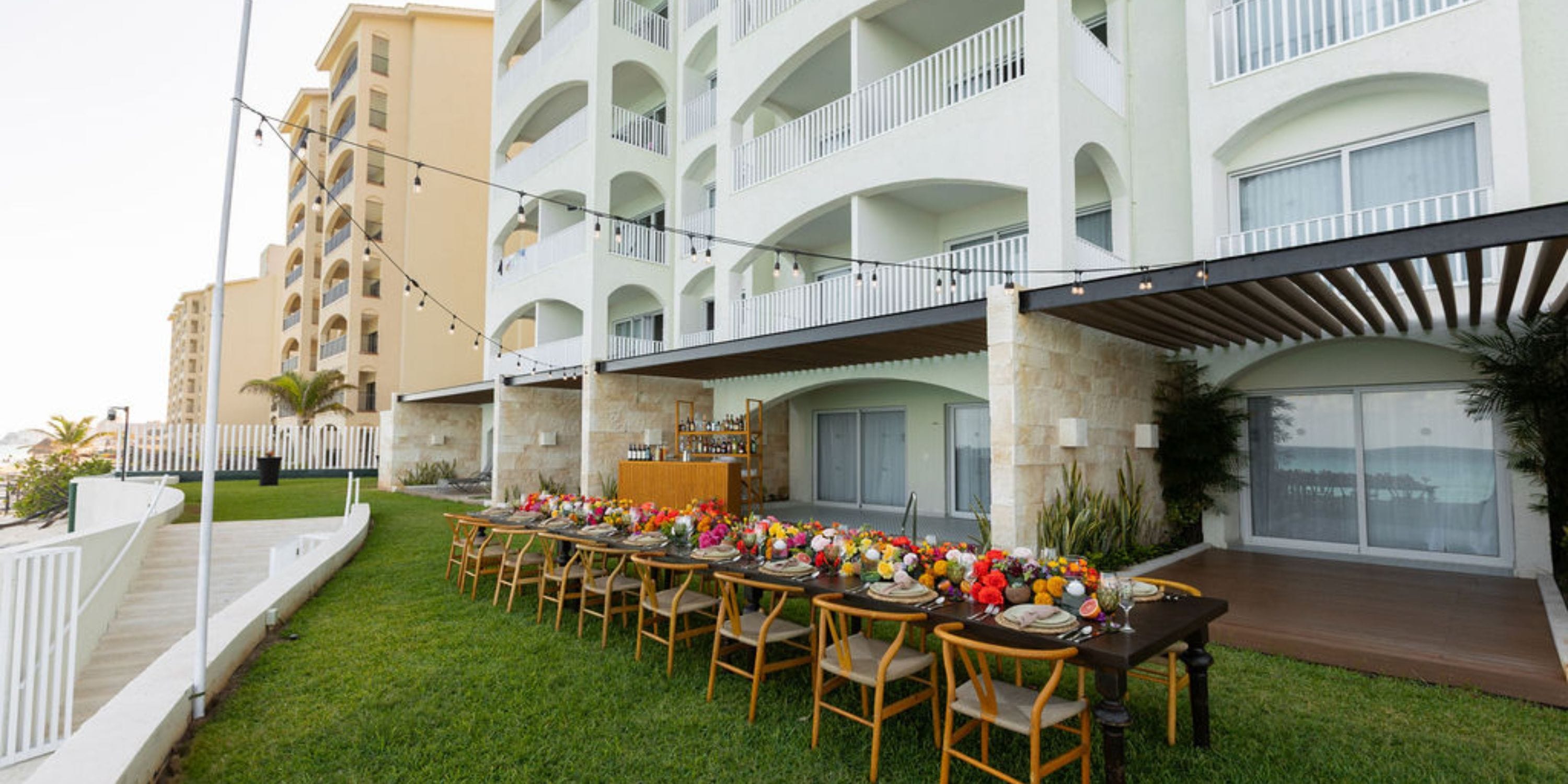 Outdoor dining table set on grass at Hilton Cancun Mar Caribe hotel balconies, ideal for destination wedding.