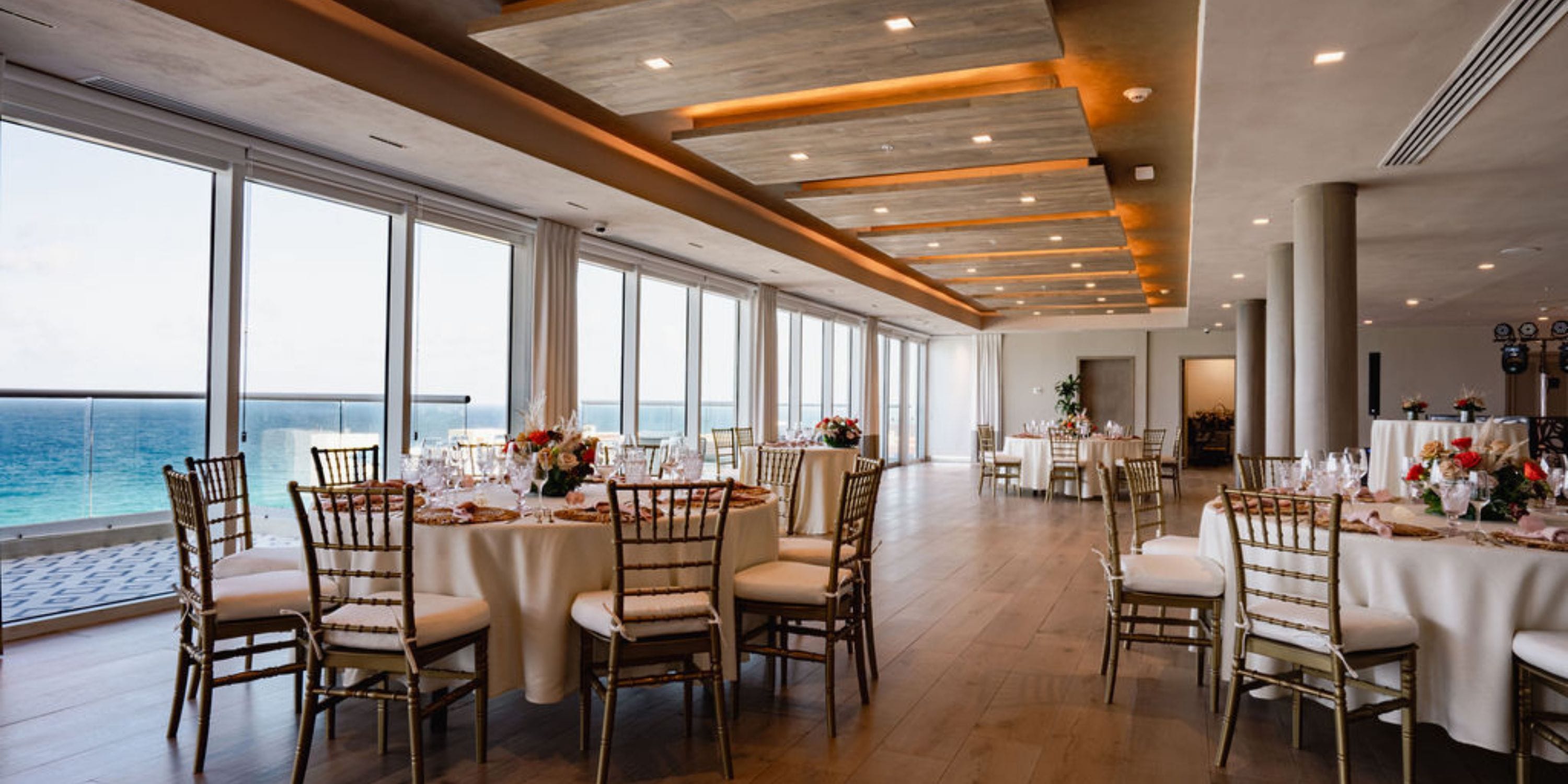 Hilton Cancun Mar Caribe: Wedding banquet hall with round tables, floral centerpieces, ocean view.