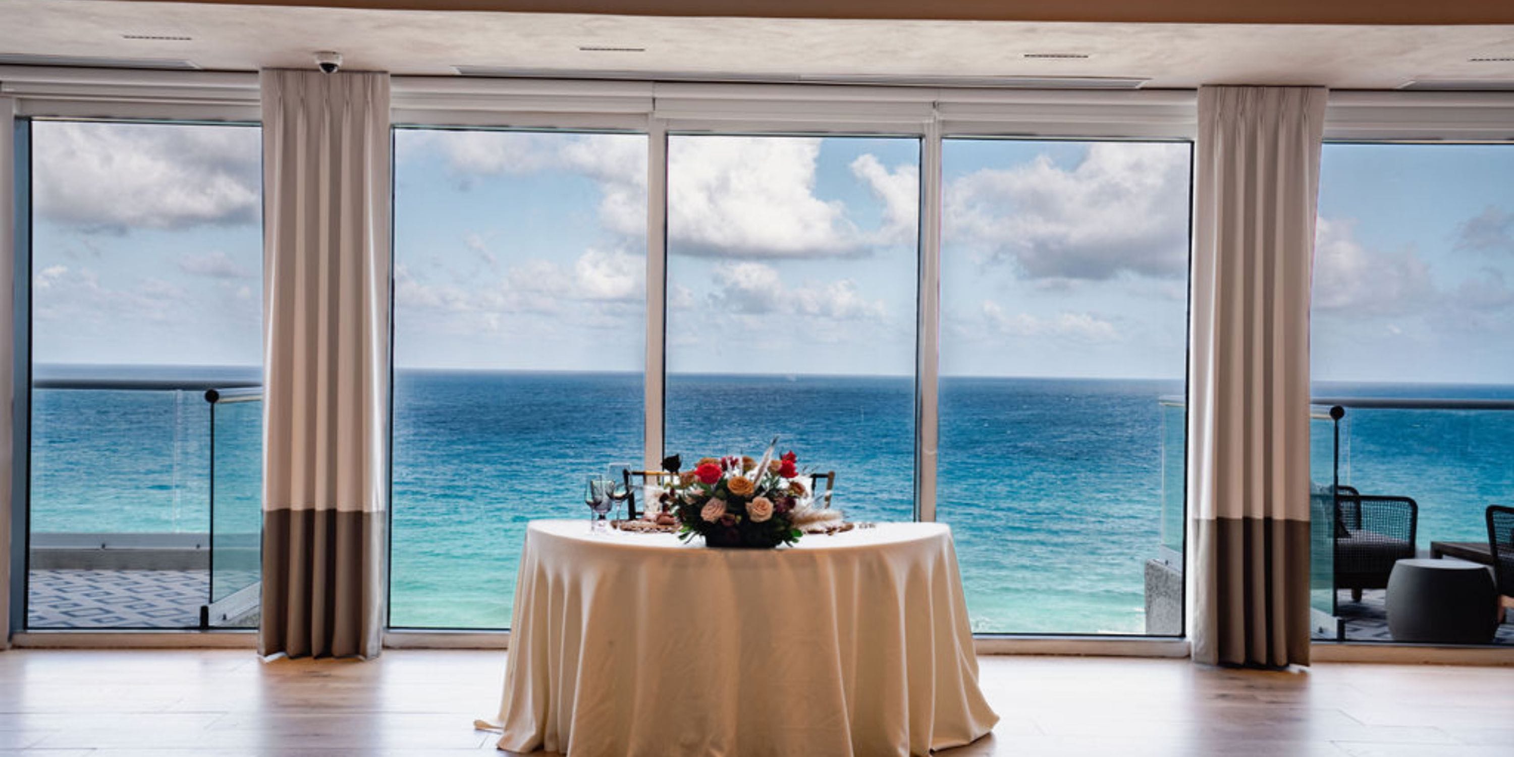 Hilton Cancun Mar Caribe wedding round table with floral centerpiece by ocean-view windows.