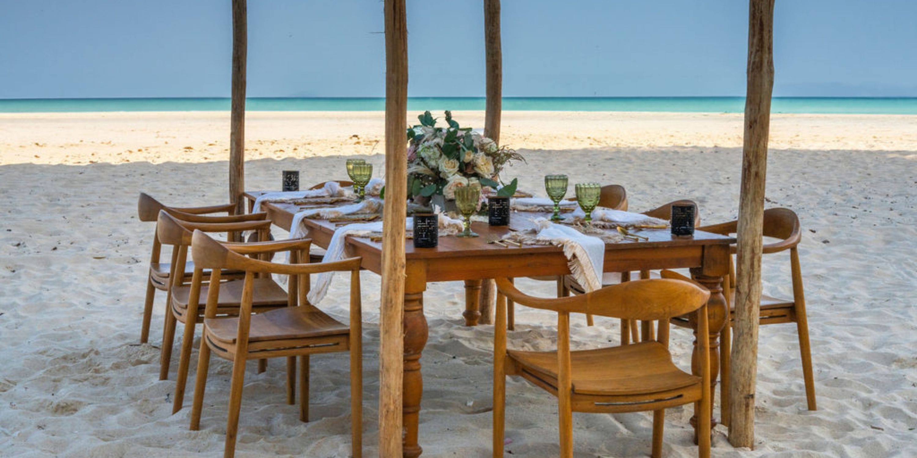 Hilton Cancun Mar Caribe: Destination wedding beachfront dining setup with table, chairs, and canopy on sand.