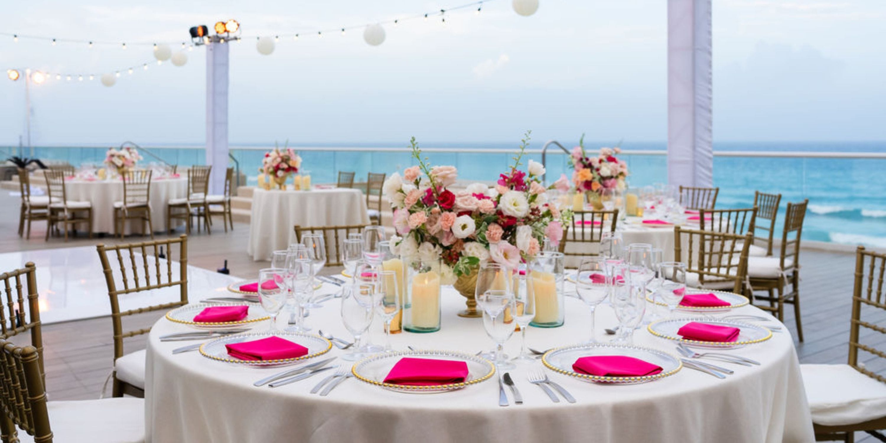 Hilton Cancun Mar Caribe destination wedding: round table with pink napkins, flowers, ocean backdrop.