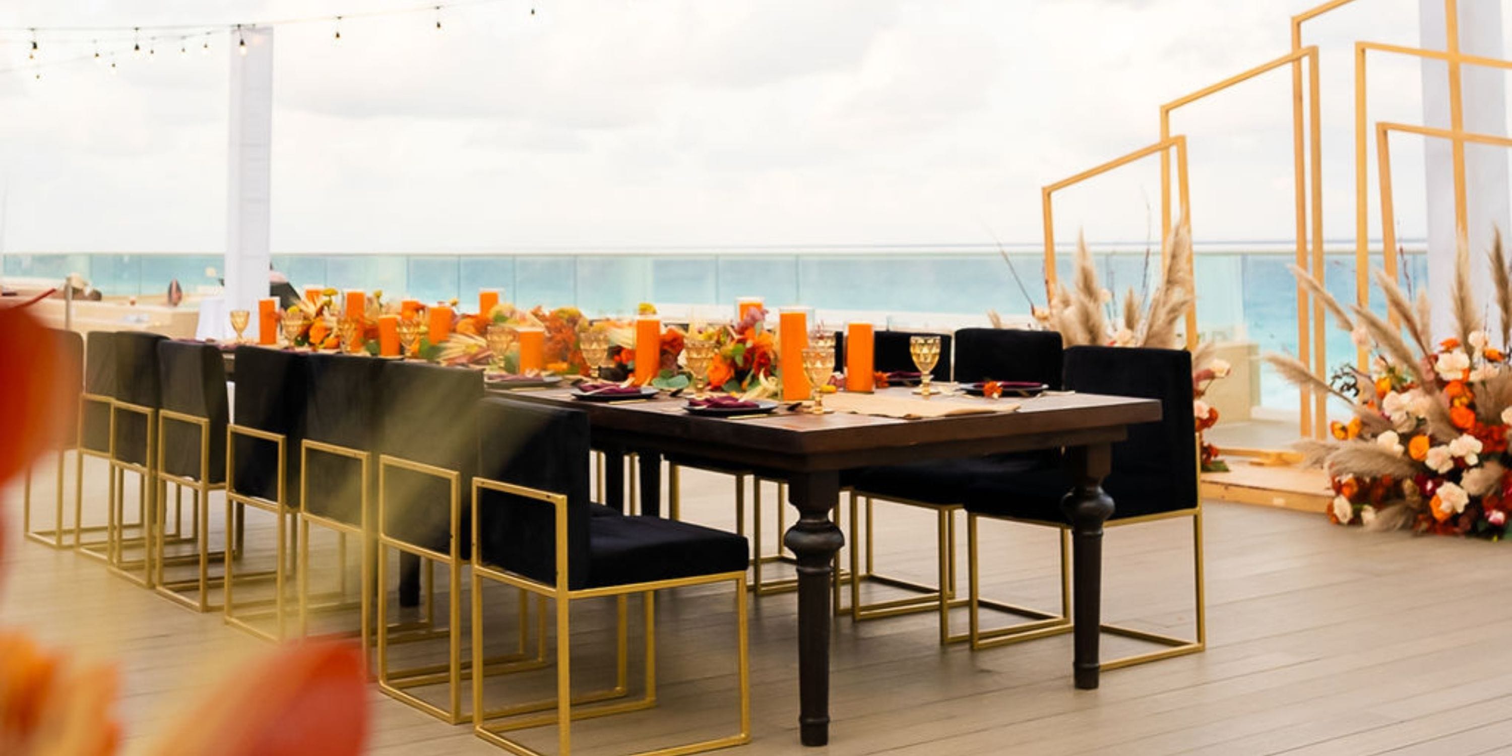 Hilton Cancun Mar Caribe wedding setup with black chairs, orange decor, and stunning ocean views.