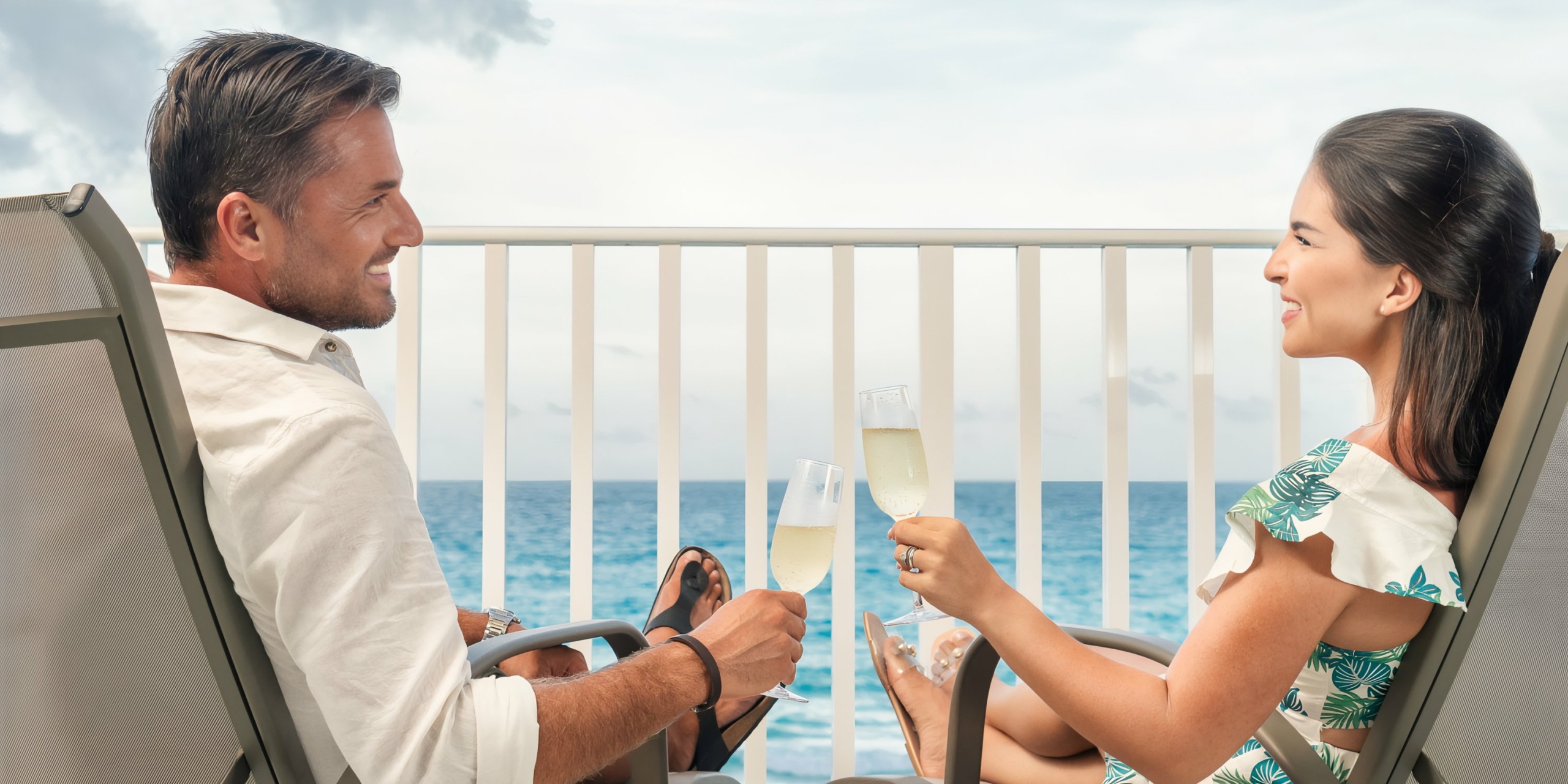 A man and a woman toasting with Hilton Cancun Mar Caribe on a balcony overlooking the sea.