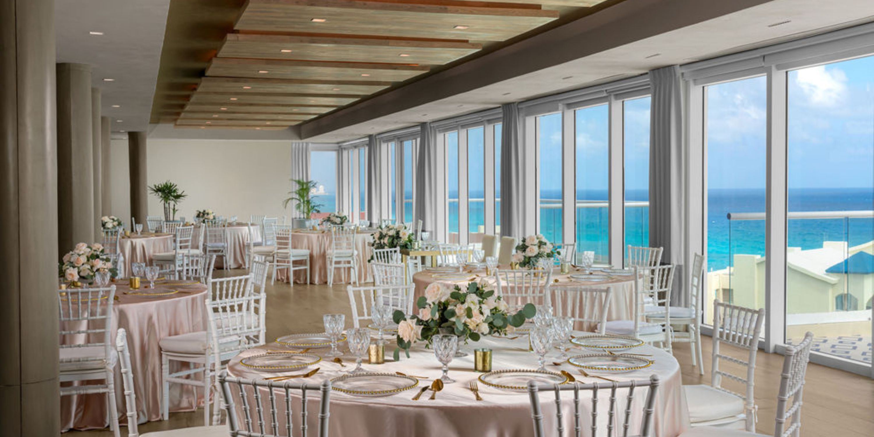 Hilton Cancun Mar Caribe: Stunning wedding banquet hall with ocean view, round tables, white chairs.