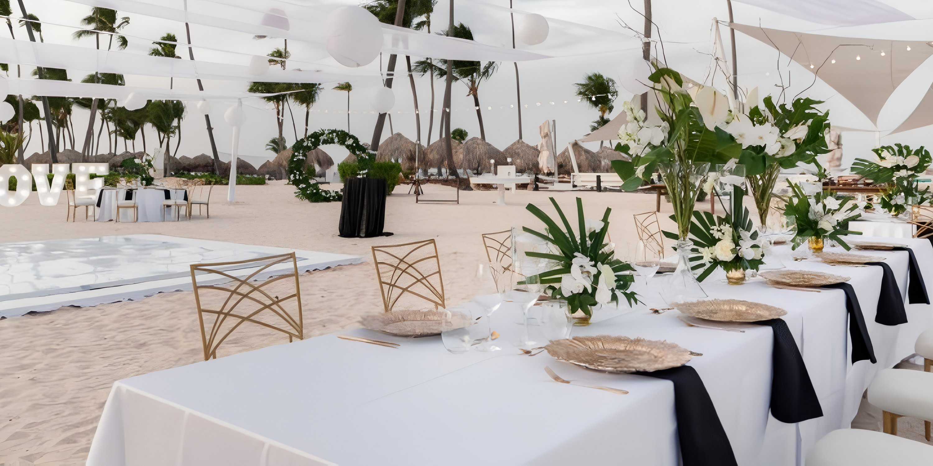 Destination wedding at JOIA Bavaro by Iberostar featuring white linens, gold chairs, and lush florals.