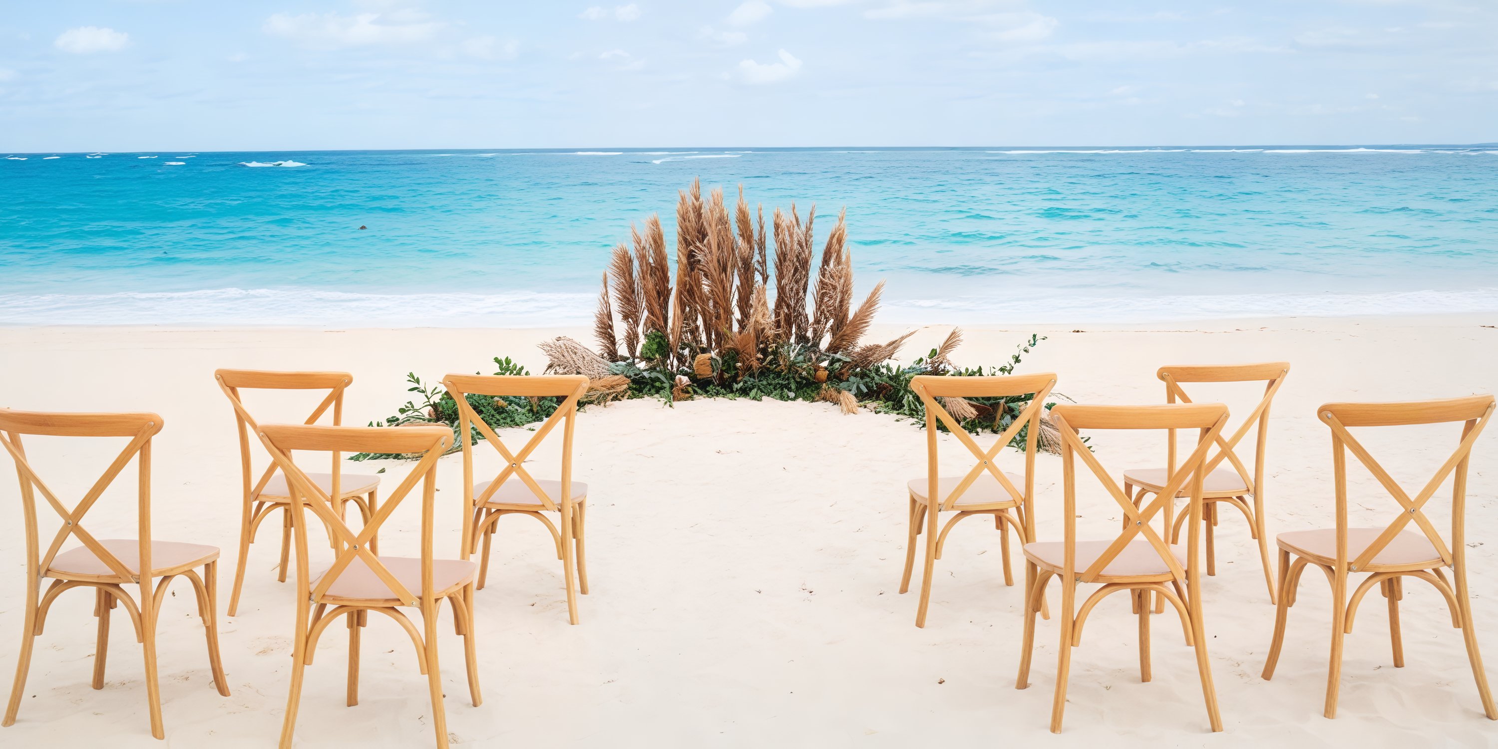 The JOIA Bavaro by Iberostar offers a stunning destination wedding setup, featuring elegantly arranged chairs and beautiful pampas grass near the ocean.
