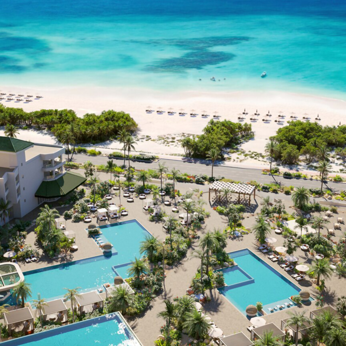 Aerial view of a beachfront resort with multiple pools, palm trees, and lounge chairs. The sandy beach and turquoise sea are in the background.