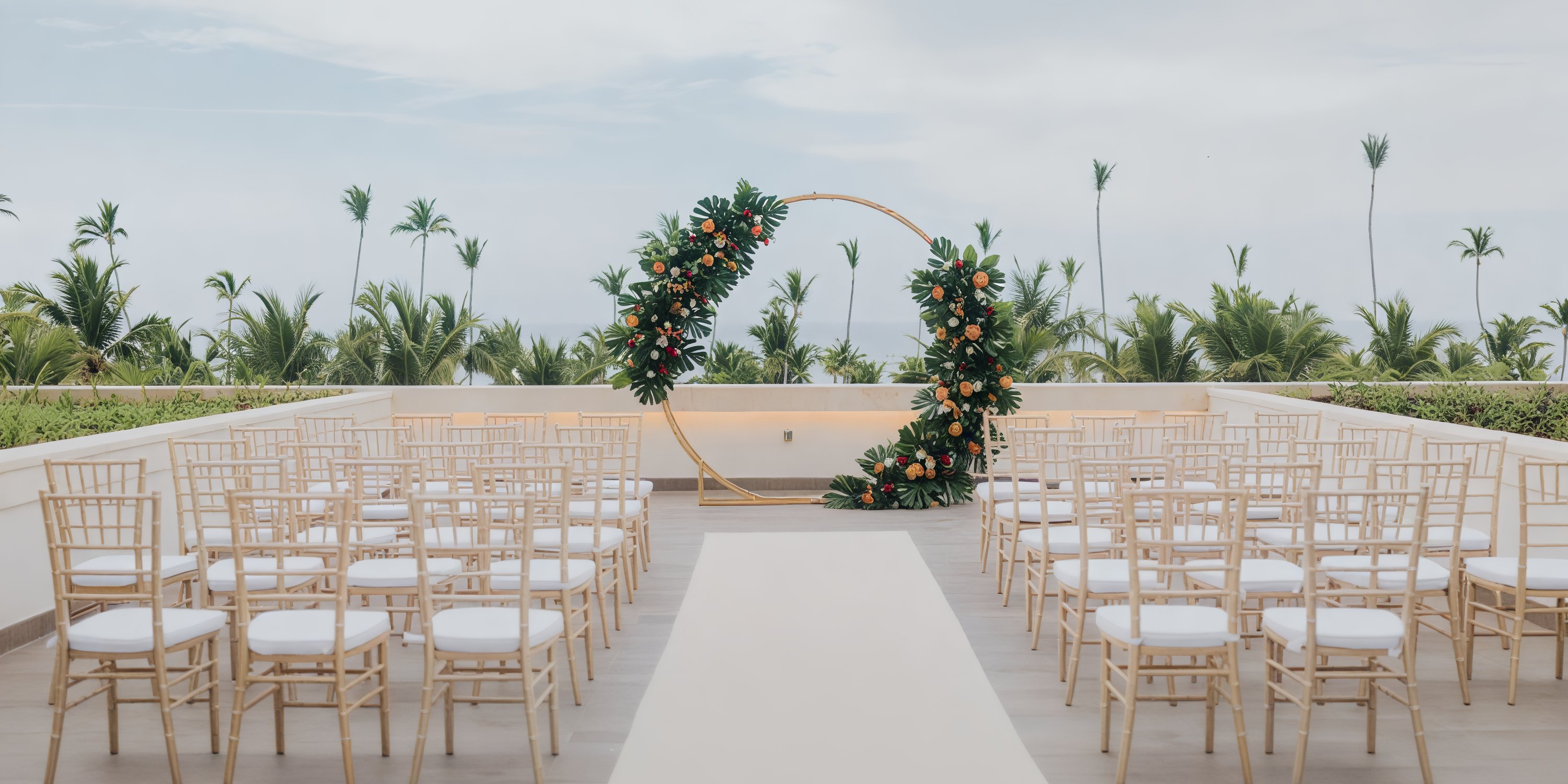 Lopesan Costa Bavaro presents a picturesque scene for a destination wedding, featuring a circular floral arch complemented by rows of chairs, perfectly arranged for an enchanting outdoor ceremony.