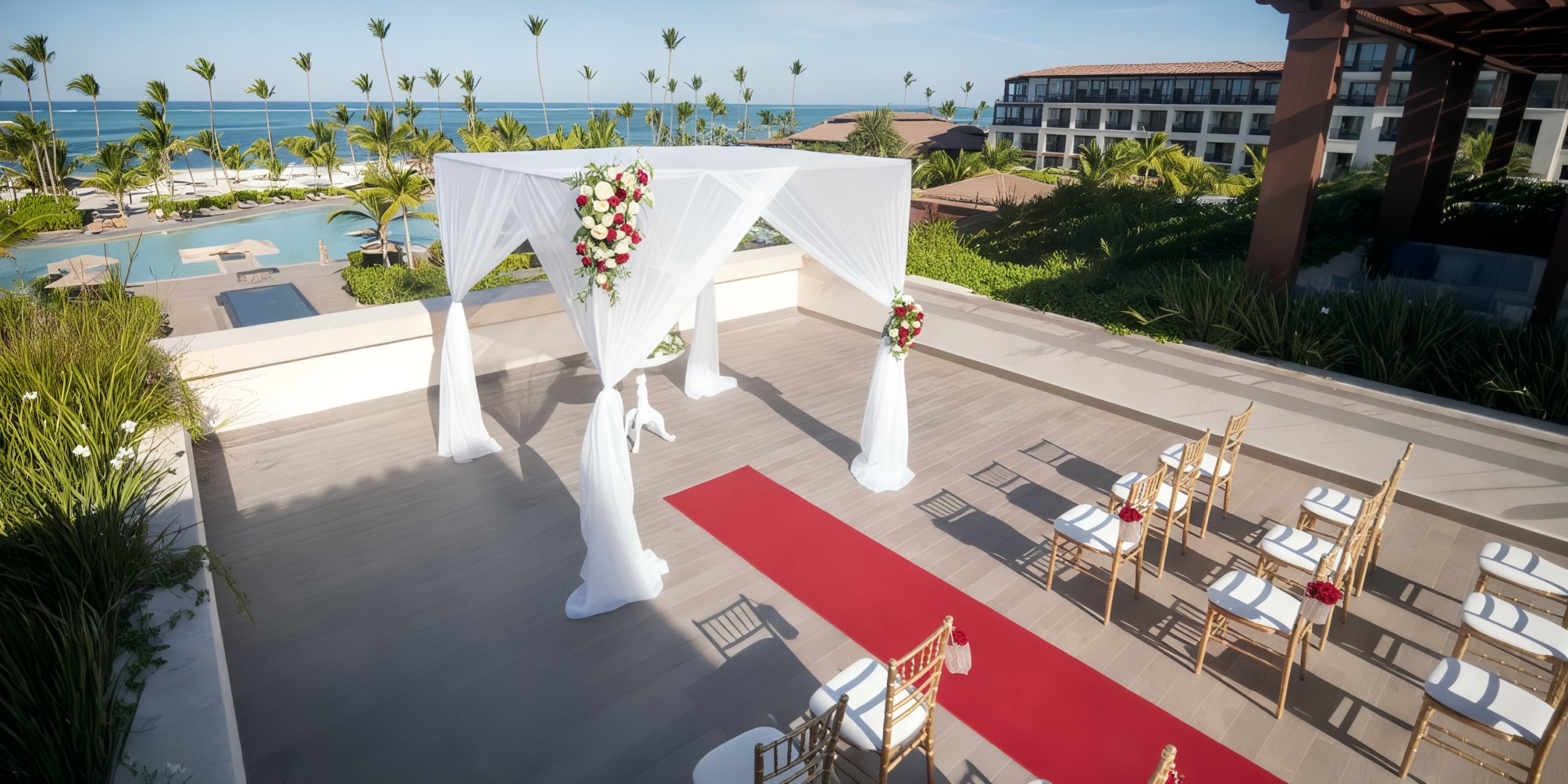 The wedding setup at Lopesan Costa Bavaro features a white canopy with a red carpet aisle and rows of chairs, complemented by the backdrop of palm trees and the ocean.