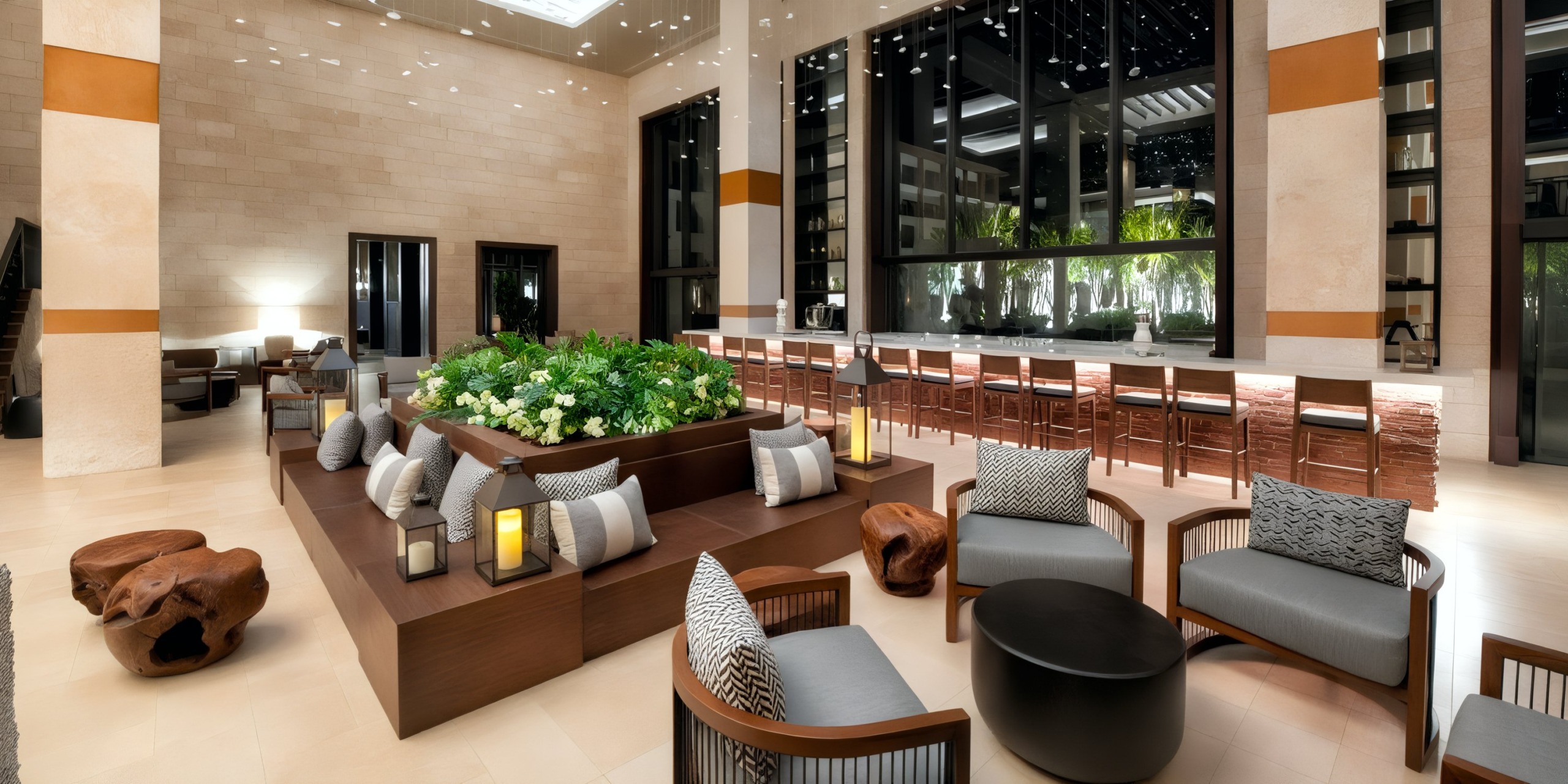 The lobby of Lopesan Costa Bavaro is spacious and modern, featuring a seating area, a central planter filled with greenery, and a long bar complete with stools. Large windows offer a view of the garden outside.