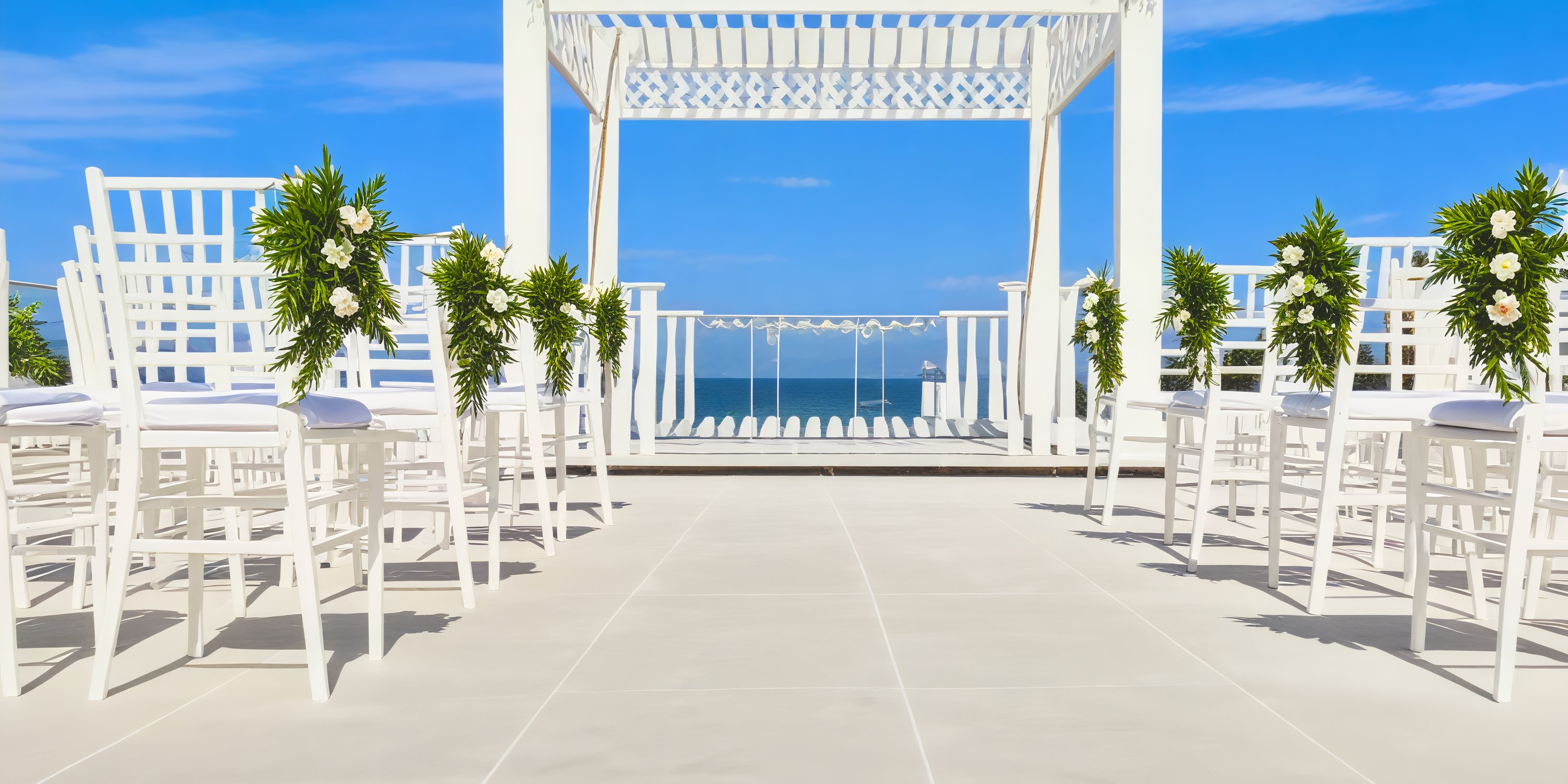 Experience a stunning destination wedding setup at Margaritaville Island Reserve Cancun, featuring elegant white chairs and beautiful florals arranged to face the breathtaking ocean backdrop.