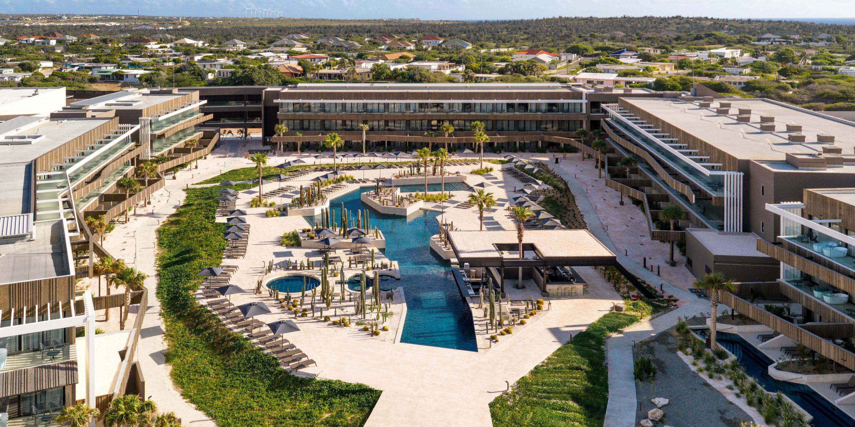 Secrets Baby Beach Aruba, ideal for a destination wedding, showcases a pool, building, and lush greenery.