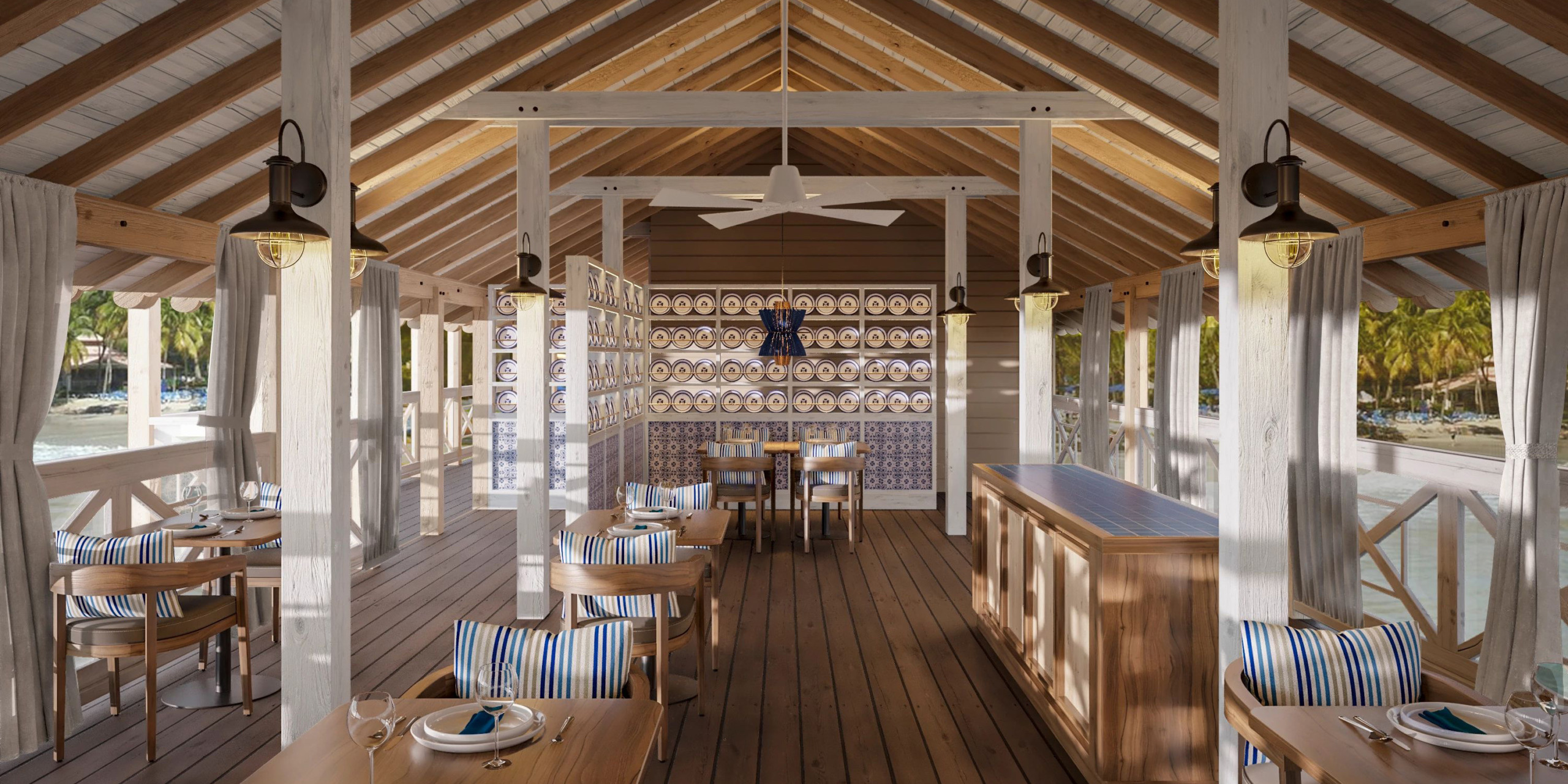 Welcome to Secrets St Lucia, our open-air restaurant featuring wooden beams, striped cushioned chairs, a cooling fan, and decorative plates adorning the walls. Our dining tables are perfectly set to provide you with stunning views of the surrounding trees and water.
