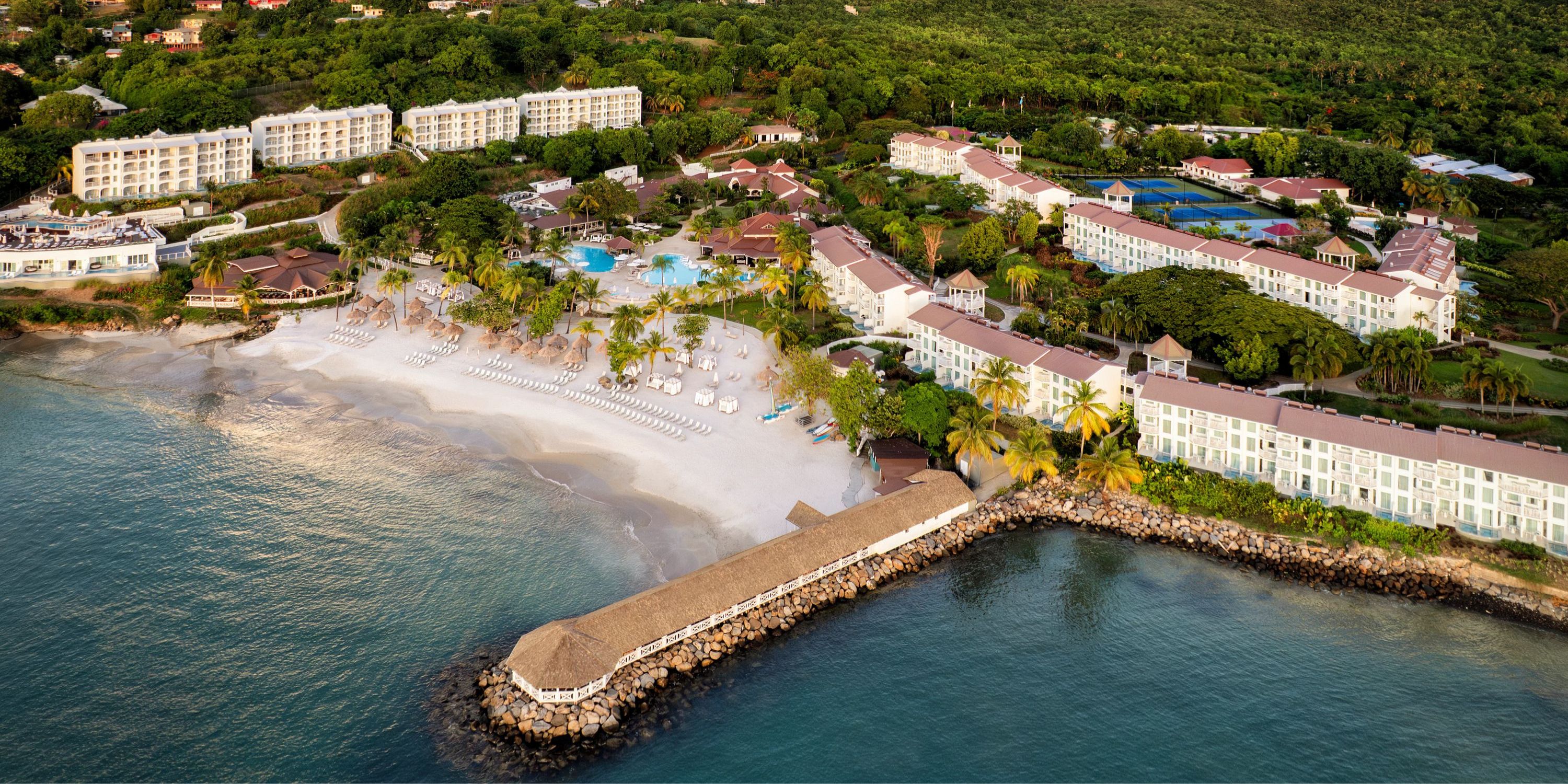 Aerial view of Secrets St Lucia resort, a lush beachfront destination wedding spot with pools and greenery.