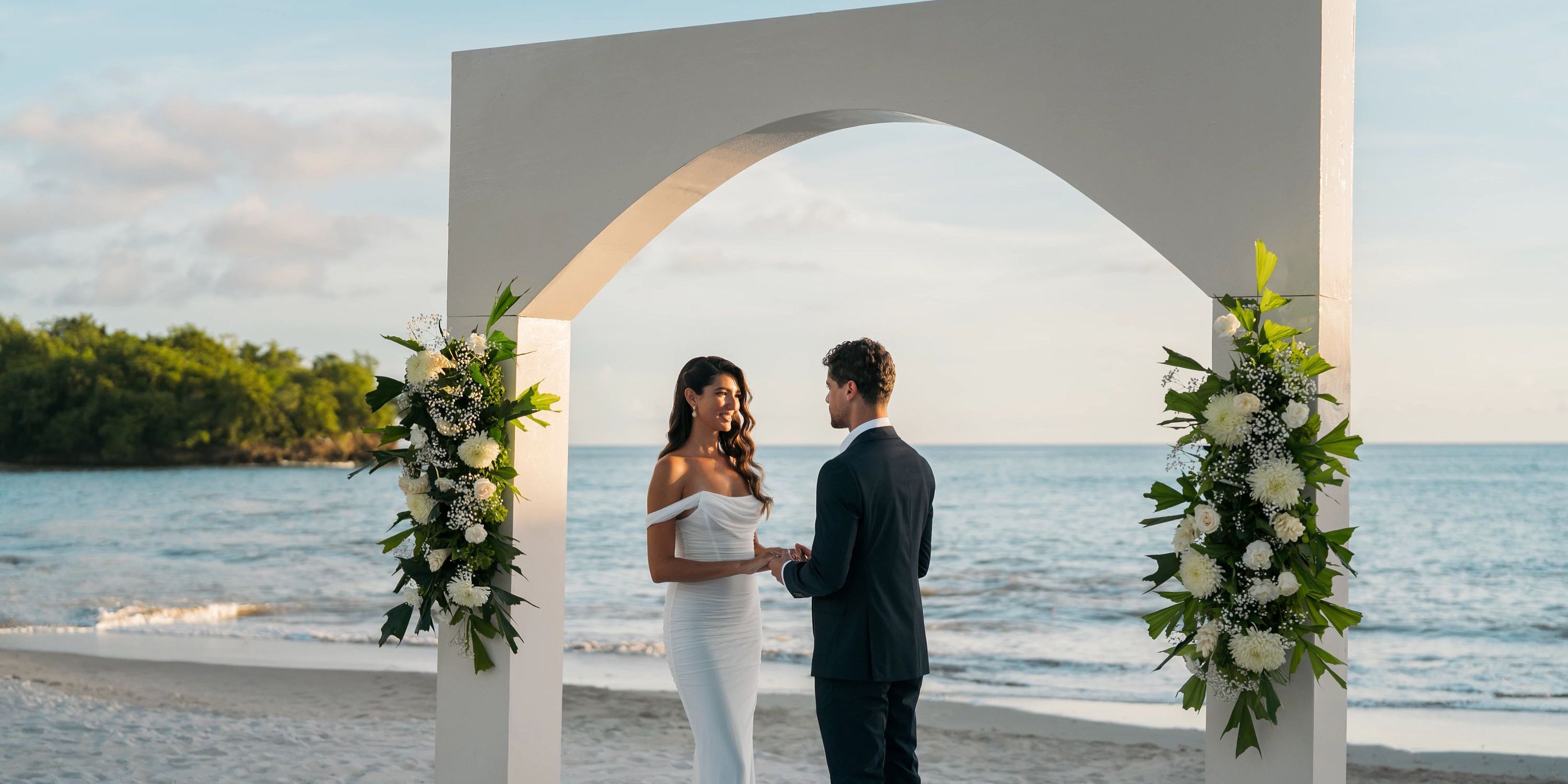 A couple holds hands beneath a floral arch during their destination wedding at Secrets St Lucia beach.