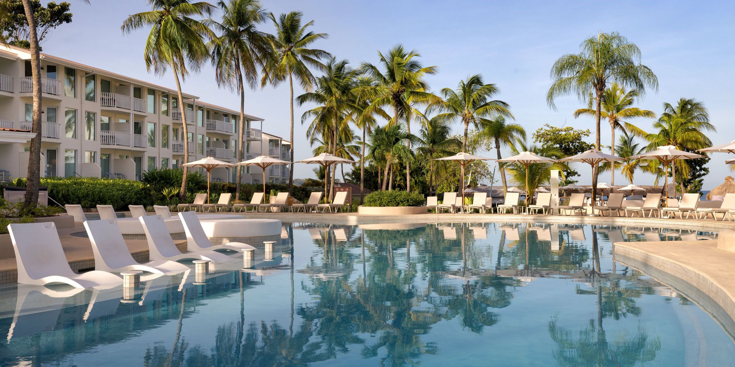 Secrets St Lucia features an outdoor pool with loungers and palm trees, ideal for a destination wedding.