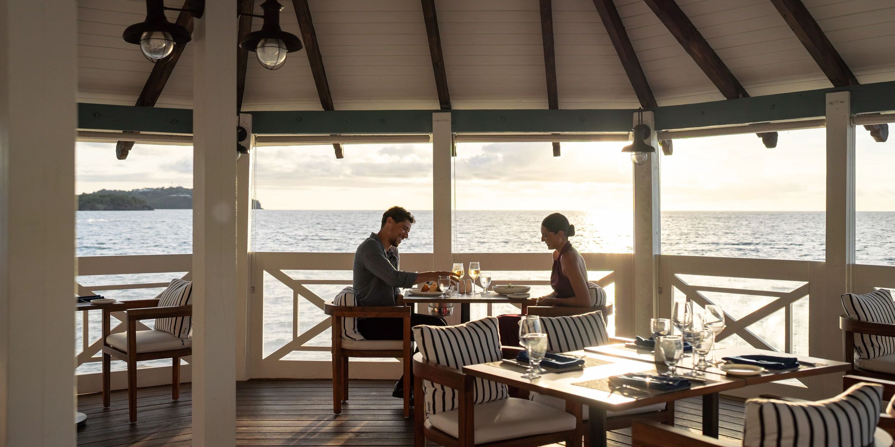 A couple dines at Secrets St Lucia during sunset, savoring seaside views after their destination wedding.