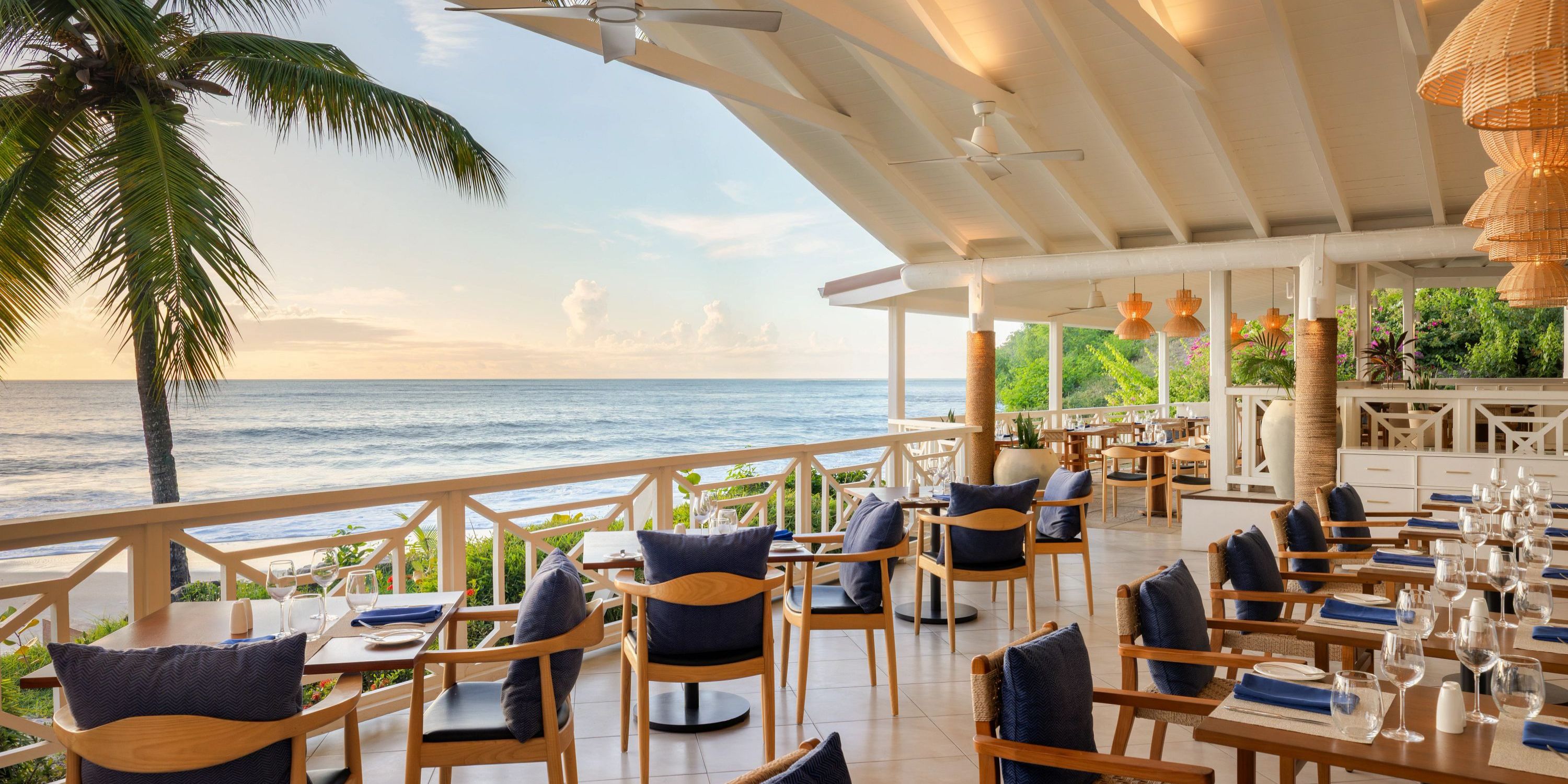 Secrets St Lucia: Beachfront dining with wooden tables, blue cushions—perfect for a destination wedding.